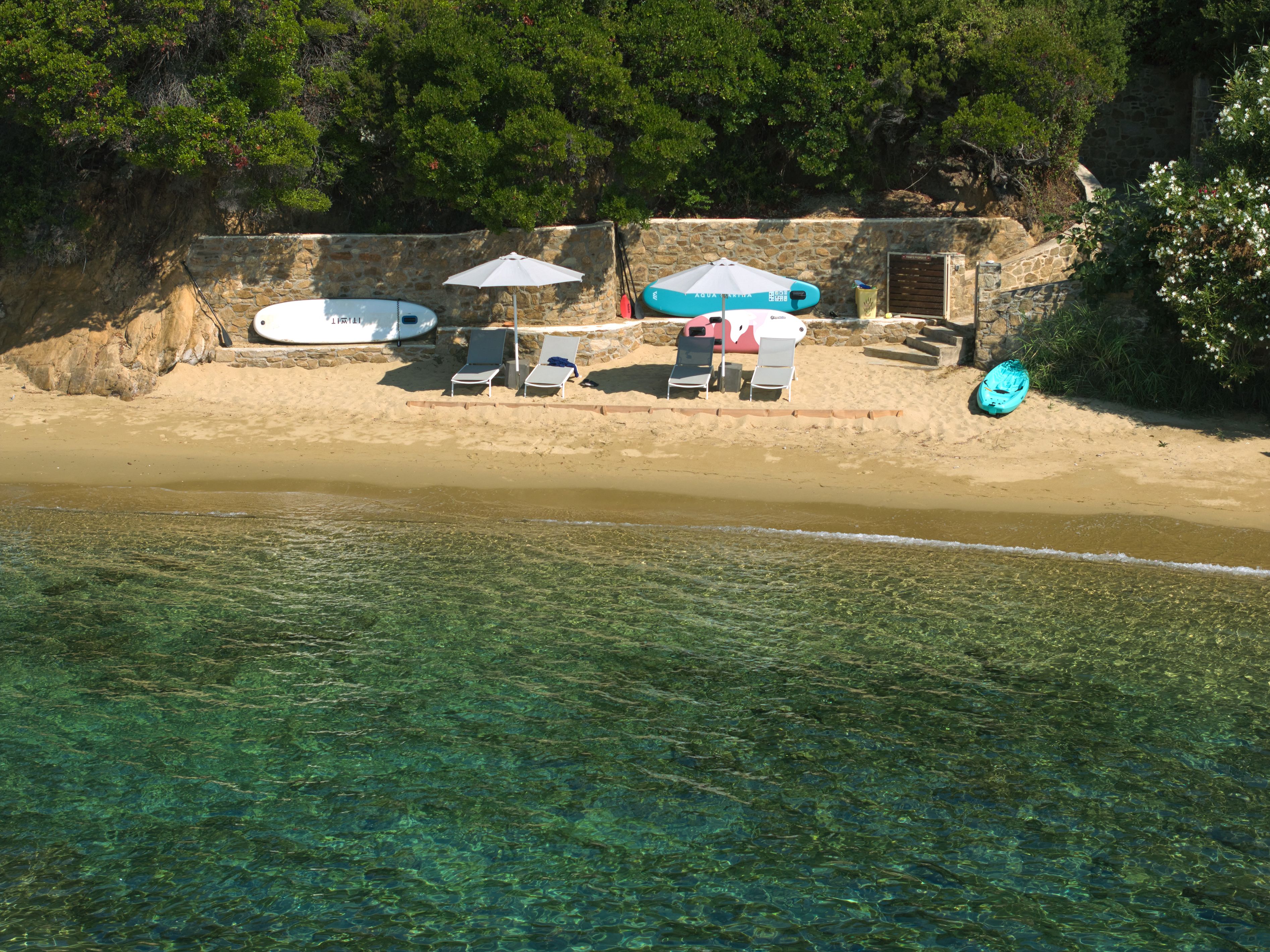 Sunbeds and umbrellas set out on the golden sand below the villas