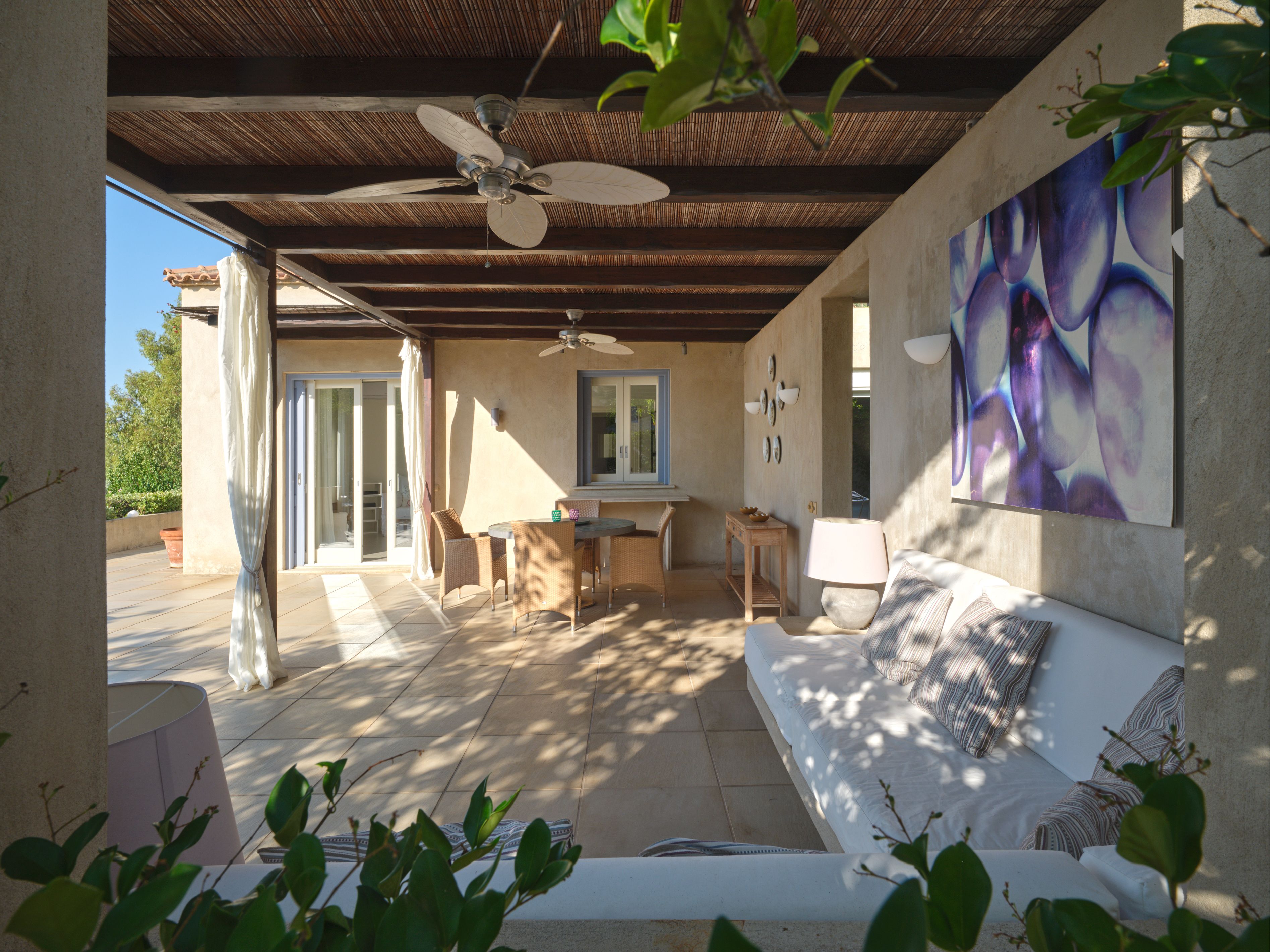 A covered living area with a ceiling fan and artwork