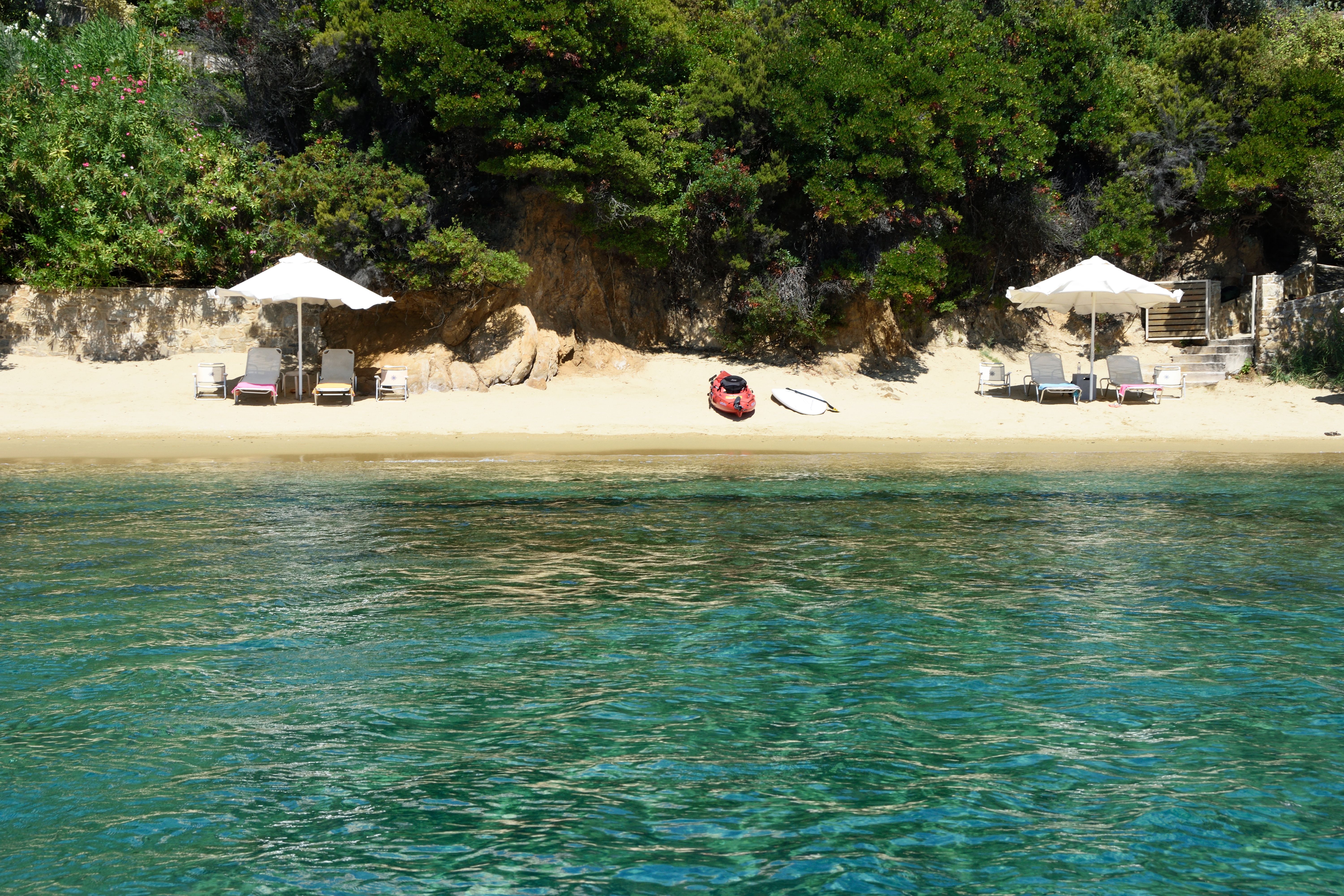 The beach and its umbrellas seen from the clear water of the bay