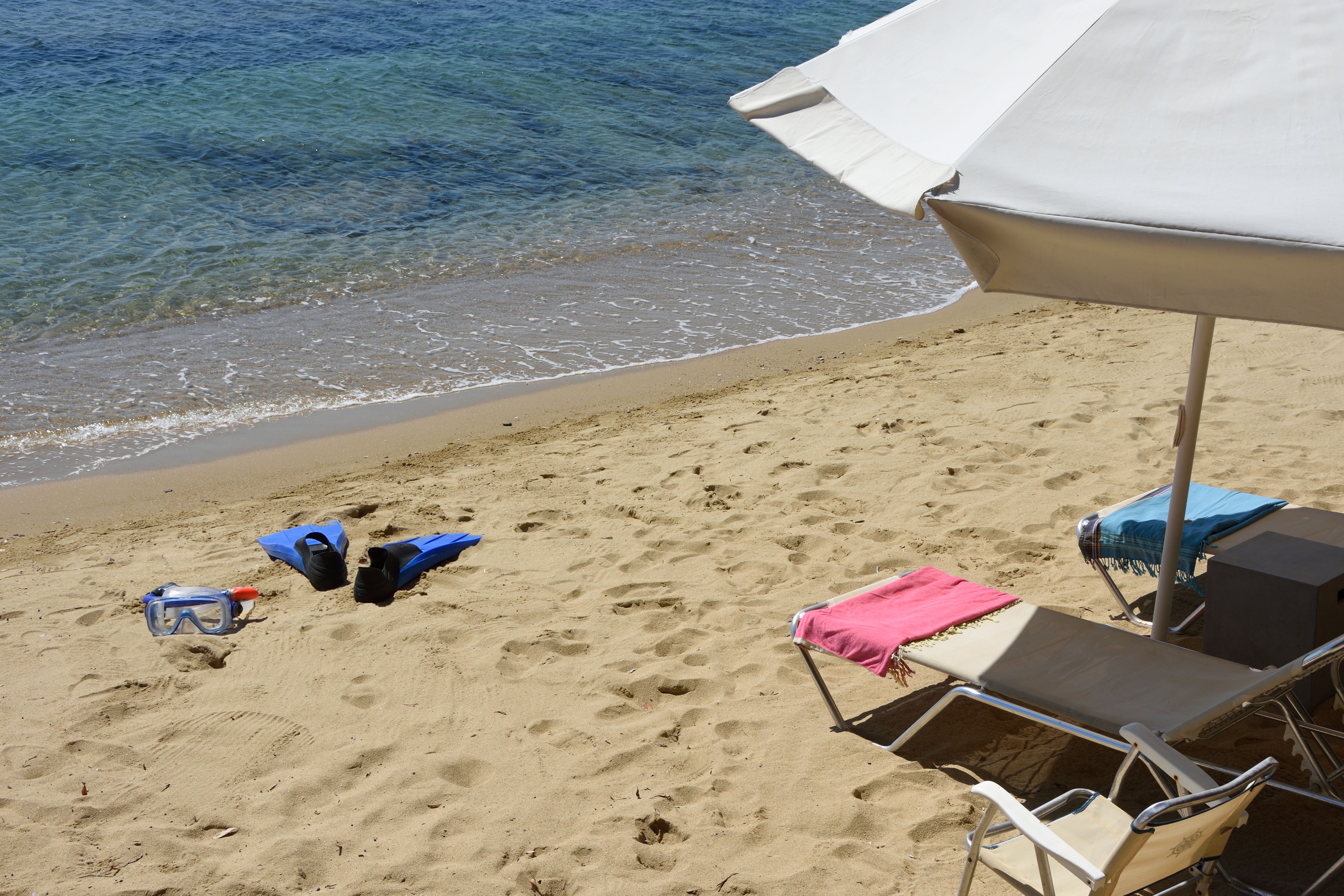 A sunbed and umbrella on the sand at the water’s edge
