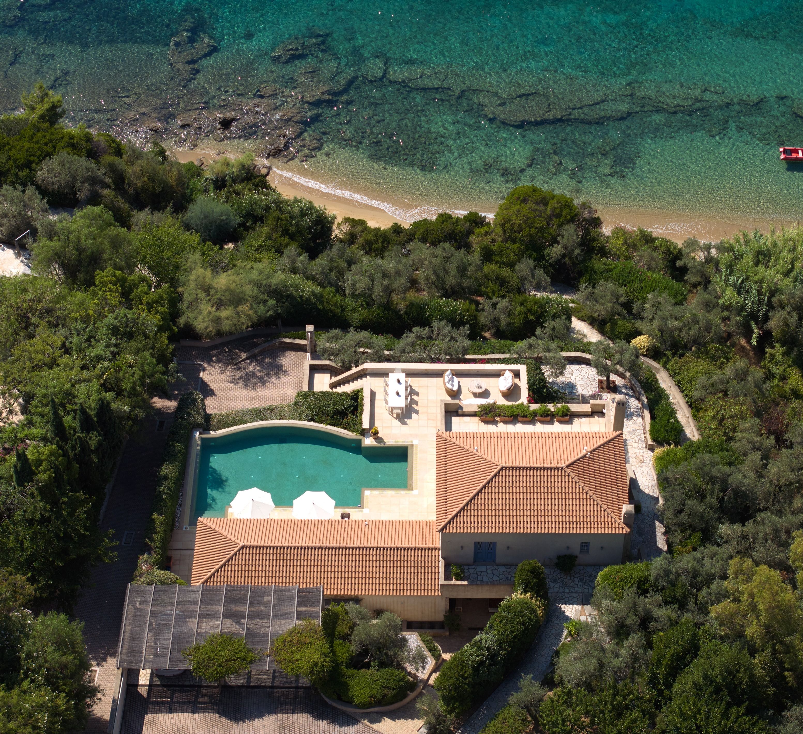 Villa Goldie and its curved infinity pool above the beach, from a drone