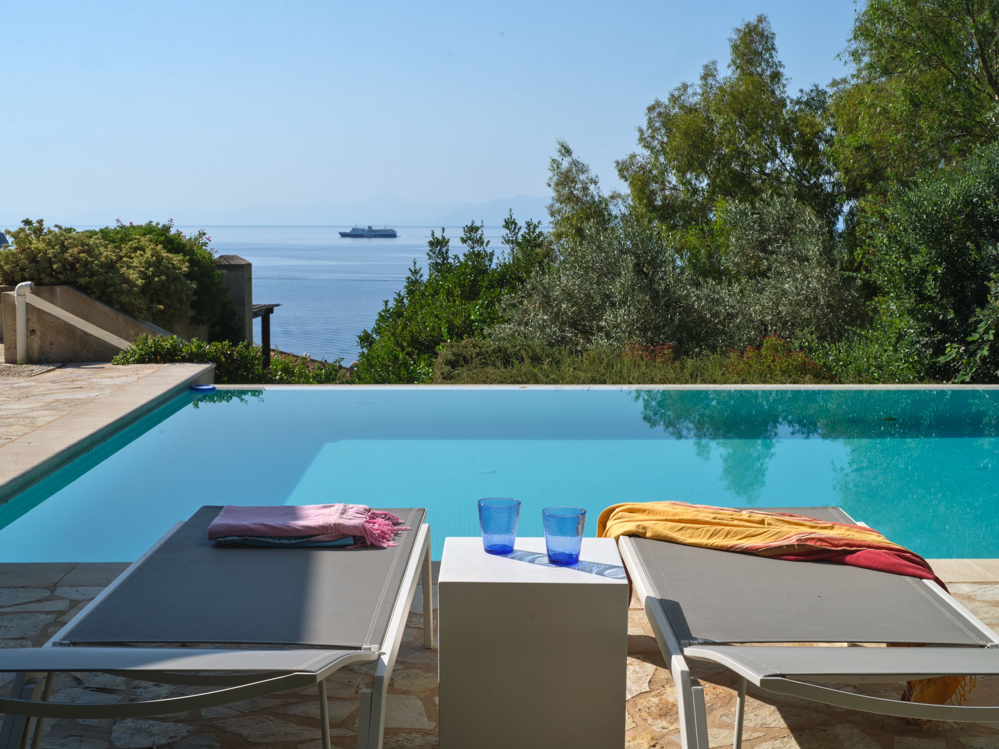 Sunbeds at the infinity edge of the pool, the sea beyond